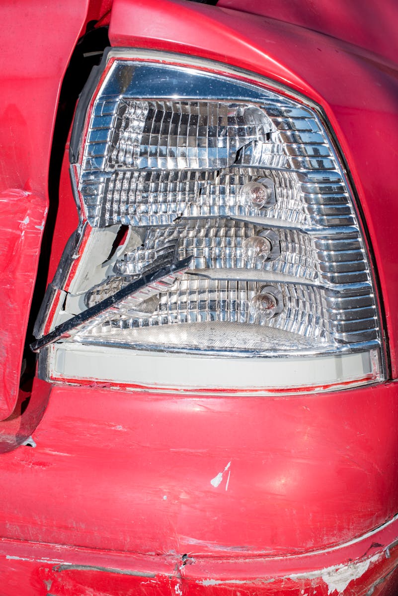 A close-up of a damaged red car tail light showing visible damage and broken glass.